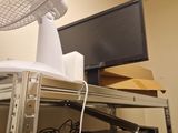 a fan sitting on top of a shelf next to a television