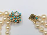 a close up of a necklace with pearls and a clasp