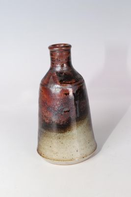 un vase brun et blanc posé sur une surface blanche