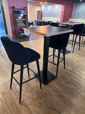 des tables et des chaises dans une grande pièce au sol en parquet et aux murs roses