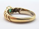 an image of a close up of a gold ring with a green stone