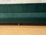 Le canapé vert est posé sur le parquet, devant la porte vitrée.