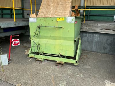 a dumpster that is sitting in front of a stop sign
