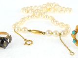 three rings, a necklace, and a ring with pearls on a white surface