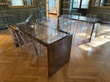une table à manger en verre entourée de chaises transparentes, au milieu de la pièce