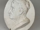 white plaster portrait of a man in profile on a white background