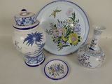 a white plate with blue and yellow flowers on it next to two vases and a plate with blue and yellow flowers on it