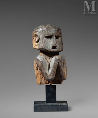 une sculpture en bois représentant une tête d'homme, posée sur un socle