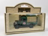 un petit camion vert dans une boîte, posé sur une surface blanche