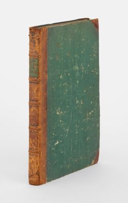 un vieux livre à la couverture verte posé sur une surface blanche