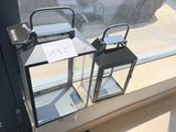 deux lanternes posées sur un rebord de fenêtre sur lequel est accrochée une pancarte