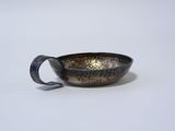 a close up of a metal bowl with a handle on a white surface