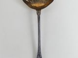 an antique spoon with a decorative design hanging on a wall