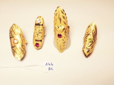 four pieces of gold and red stones on a white surface