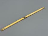 an old brass ruler with a wooden handle on a gray surface