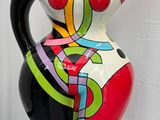 un vase coloré posé sur un socle noir au sol