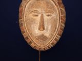 a wooden mask on a stand against a blue background