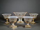 six white and gold striped vases on pedestals against a gray background