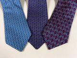 three different colored ties on a white surface with one blue and one red