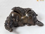 un petit éléphant en bronze avec une selle sur le dos
