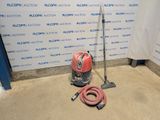 un aspirateur et un tuyau posés par terre devant un mur