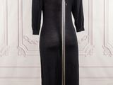 black dress on a mannequin stand in front of a white wall