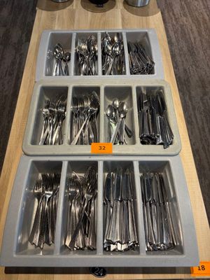 de nombreuses cuillères et fourchettes dans un plateau posé sur une table
