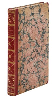 un vieux livre à la couverture rouge posé sur une surface blanche