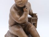 statue of a child sitting on a box with a basket in his hand
