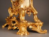 a gold clock that is on a stand with a clock on it