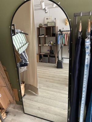 a mirror in the corner of a room with clothes on racks