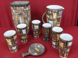 seven cups and a pitcher sitting on a red table