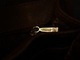 the zipper of a brown purse with a gold metal clasp