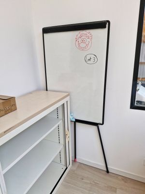 un tableau blanc accroché au mur à côté d'une bibliothèque