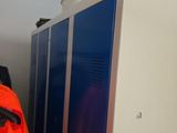 un homme vêtu d'une veste orange, debout devant un casier