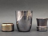 three silver cups and a silver vase on a table