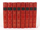 six red books lined up in a row on a white surface