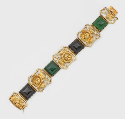 un gros plan d'un bracelet doré et vert posé sur une surface blanche