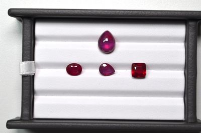 three ruby gems are displayed in a display case on a white surface