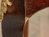 a close up of a wooden chair with a gold decoration on it