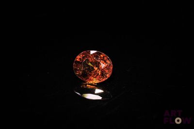 a close up of an orange diamond on a black surface