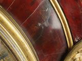 a close up of a gold and red clock on a table