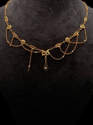 un collier en or orné de perles et de chaînes, posé sur un mannequin