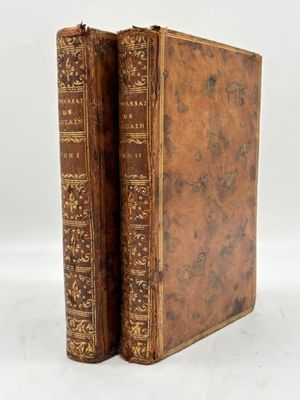 an old book with a brown cover sitting on top of a white surface
