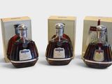 trois bouteilles de brandy posées les unes à côté des autres sur une surface blanche