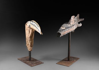 paire de têtes d'oiseaux sculptées sur des socles, sur fond noir