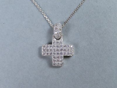 un gros plan sur un pendentif en forme de croix suspendu à une chaîne en argent