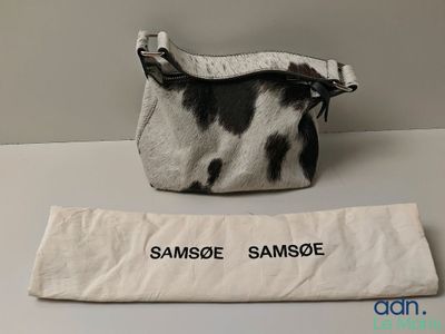 a black and white cow print bag next to a white bag