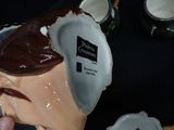 a person holding a cup with a chocolate frosting inside of it