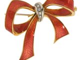 une image représentant une broche en forme de nœud rouge et or, sertie de diamants